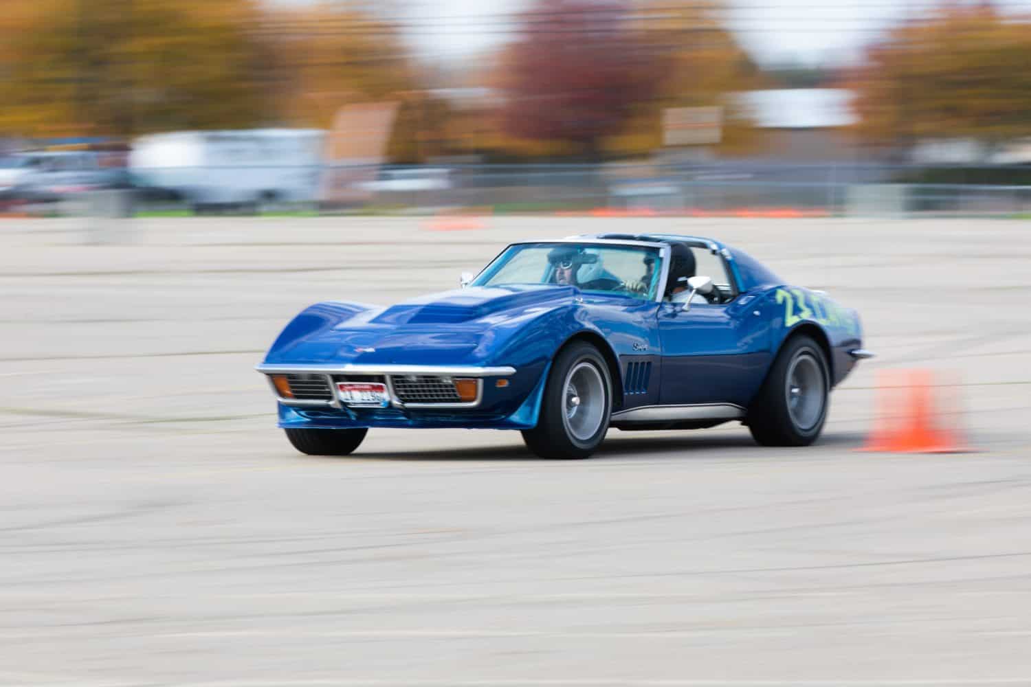 Boise, Idaho - October 31, 2021: A classic blue Corvette speeds around a race track, depicted with motion blur to emphasize the thrill of racing. The scene exudes excitement and dynamic energy.