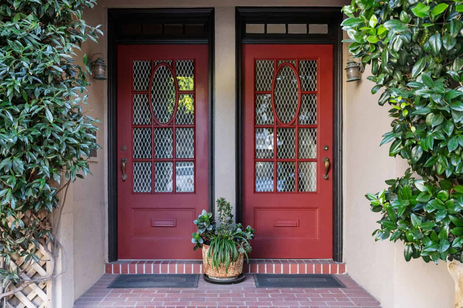 two red front doors with plants and a brick entrance way