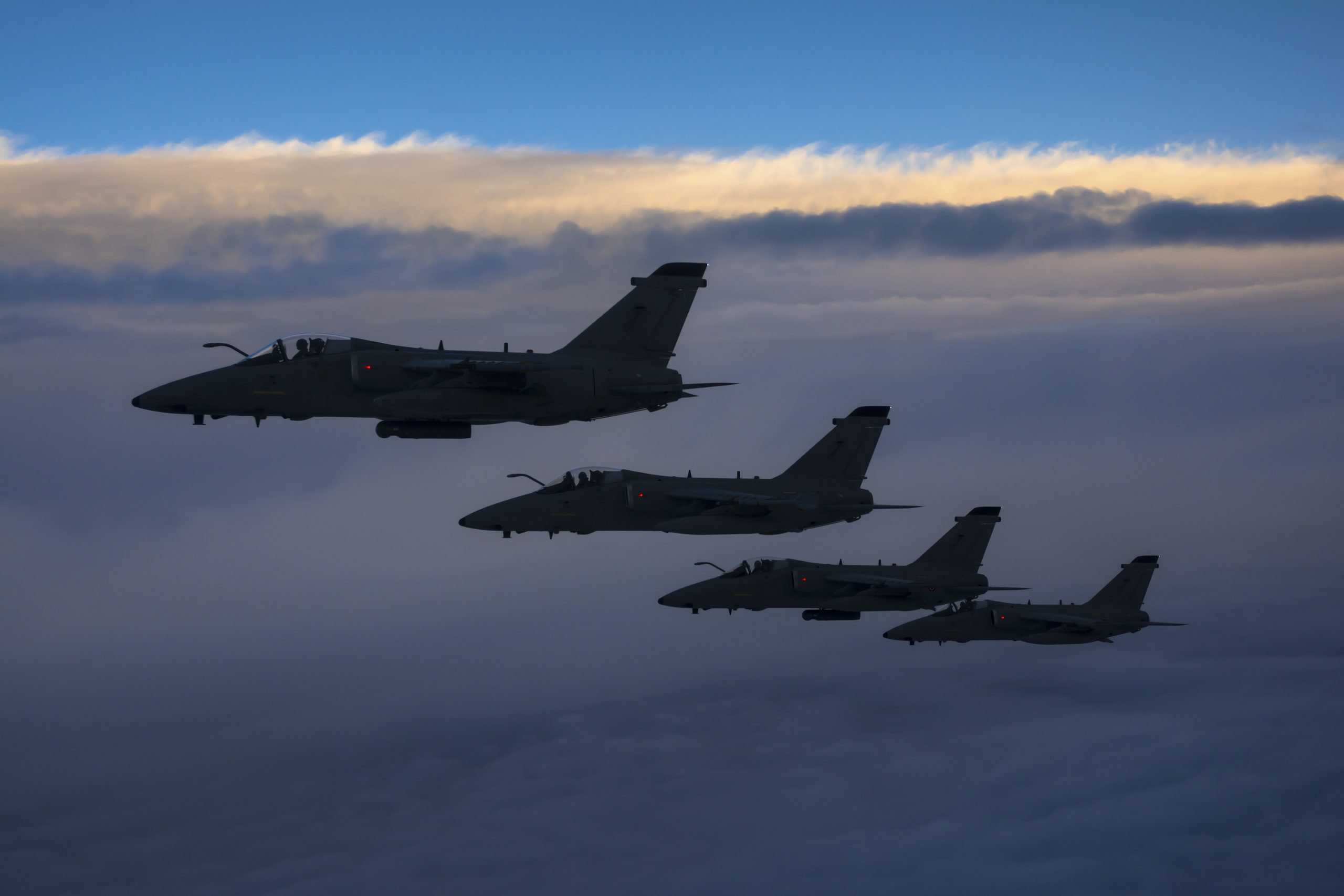 Four Italian Air Force AMX aircraft flying over the Tyrrhenian Sea during an air-to-air refueling operation.