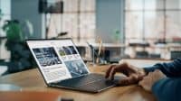 Close up on Hands of Caucasian Man Using Laptop Computer for Reading Latest News. Freelance Male is Doing Financial Market Analysis and Report for Clients and Employer in Cozy Creative Living Room.