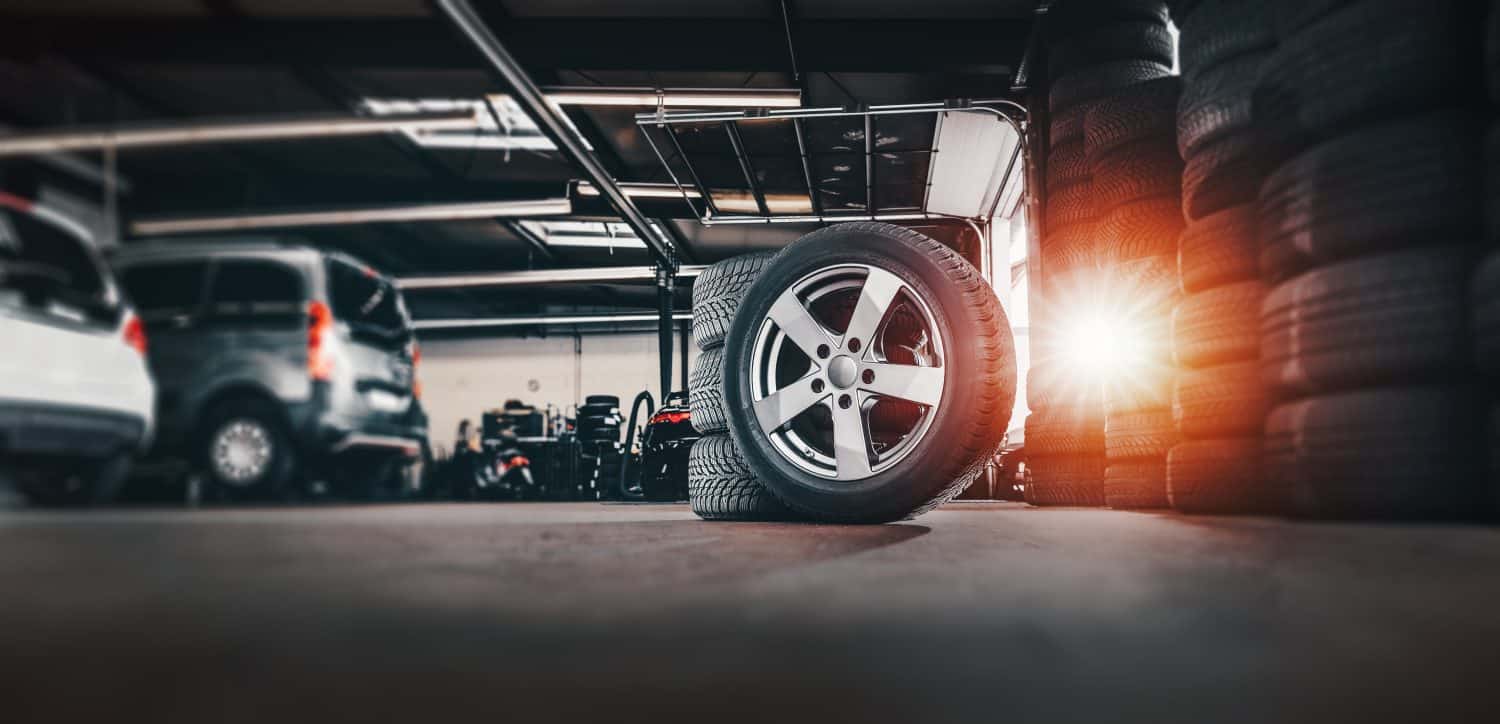 tire at repairing service garage background. Technician man replacing winter and summer tyre for safety road trip. Transportation and automotive maintenance concept