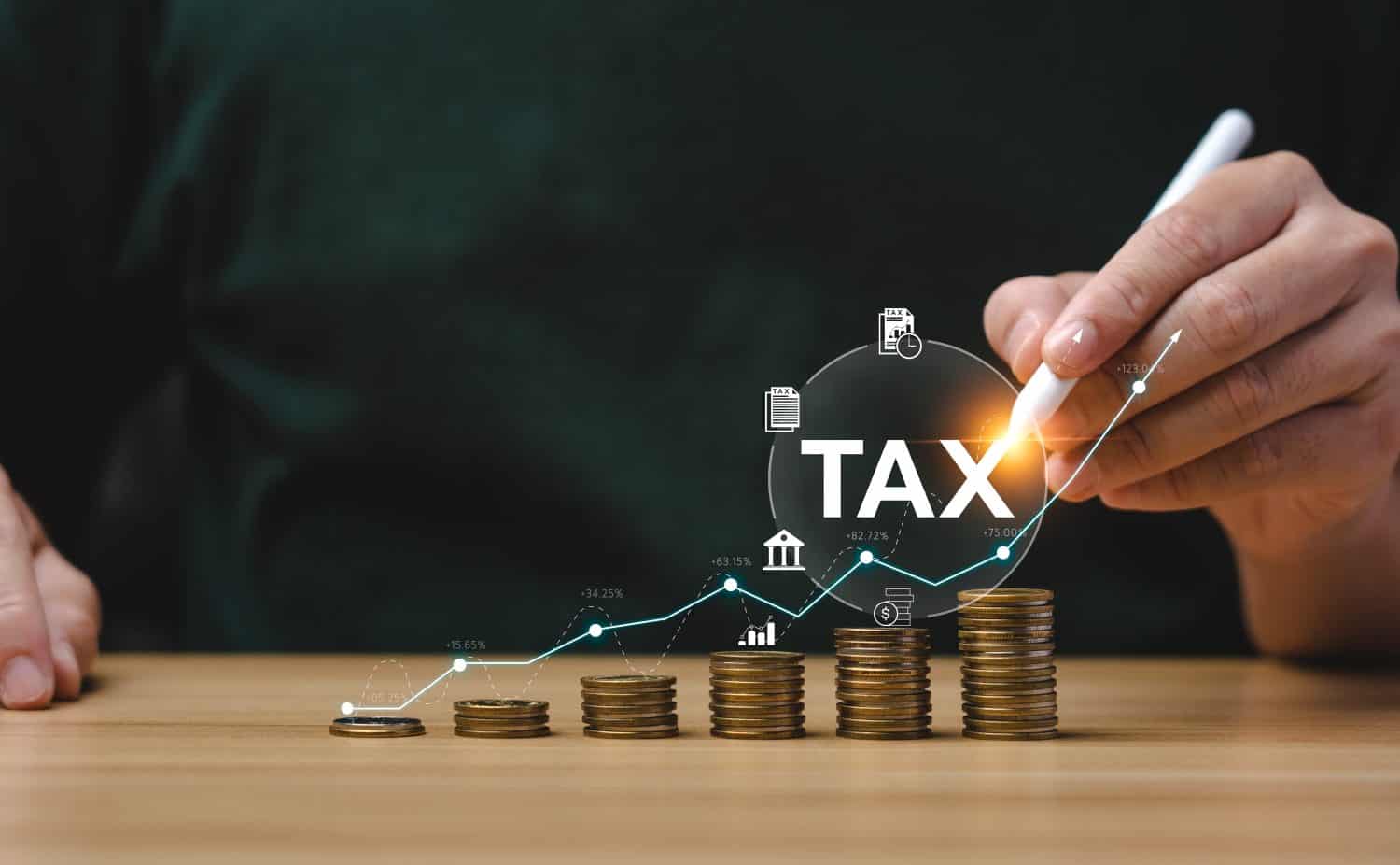 Tax deduction planning concept. Expenses, account, VAT, income tax, and property tax, pay tax. Businessman's hand and pile of coins on the table.