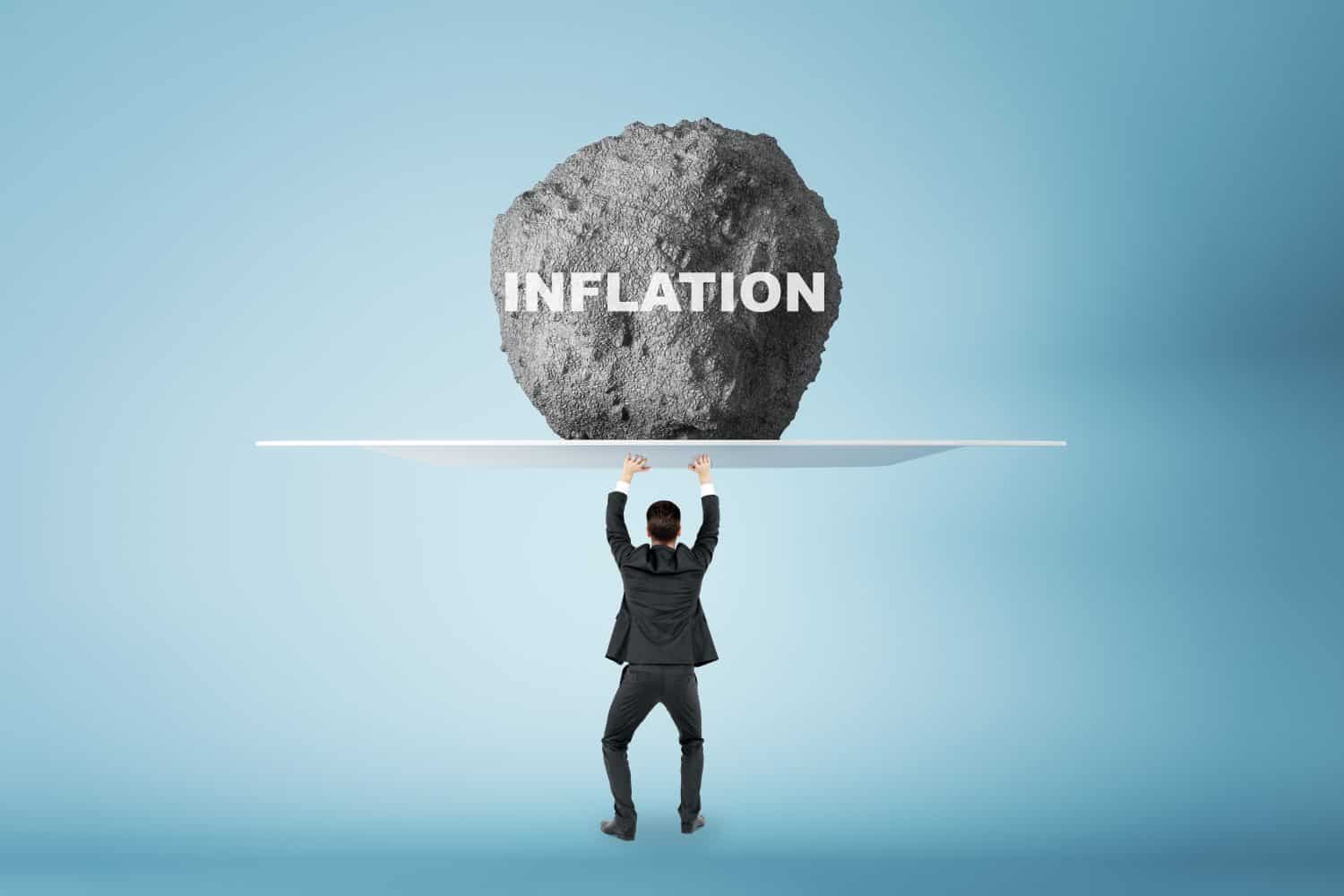 Crisis and anti-crisis management concept with businessman back view holding huge stone with inflation sign above his head, feeling tired on light background