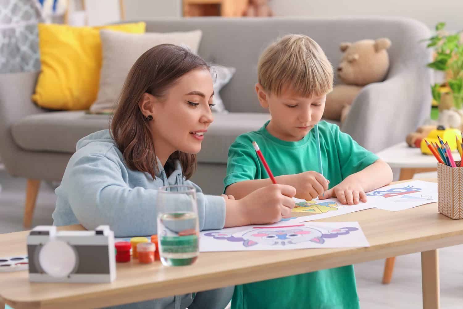 Nanny with little boy drawing at home