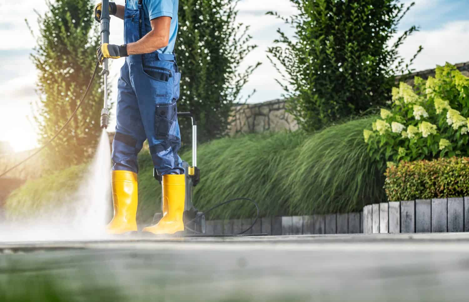 Worker Pressure Washing Residential Driveway Using Modern Pressure Washer