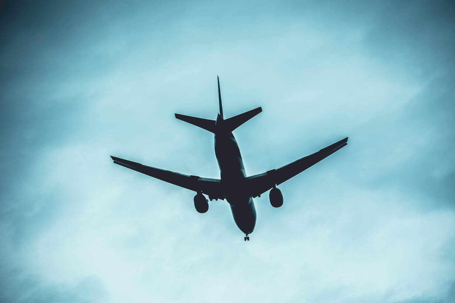 Shadow darkness or dark side of airplane flying travel flight plane loss concept, silhouette of aeroplane on dark blue sky.