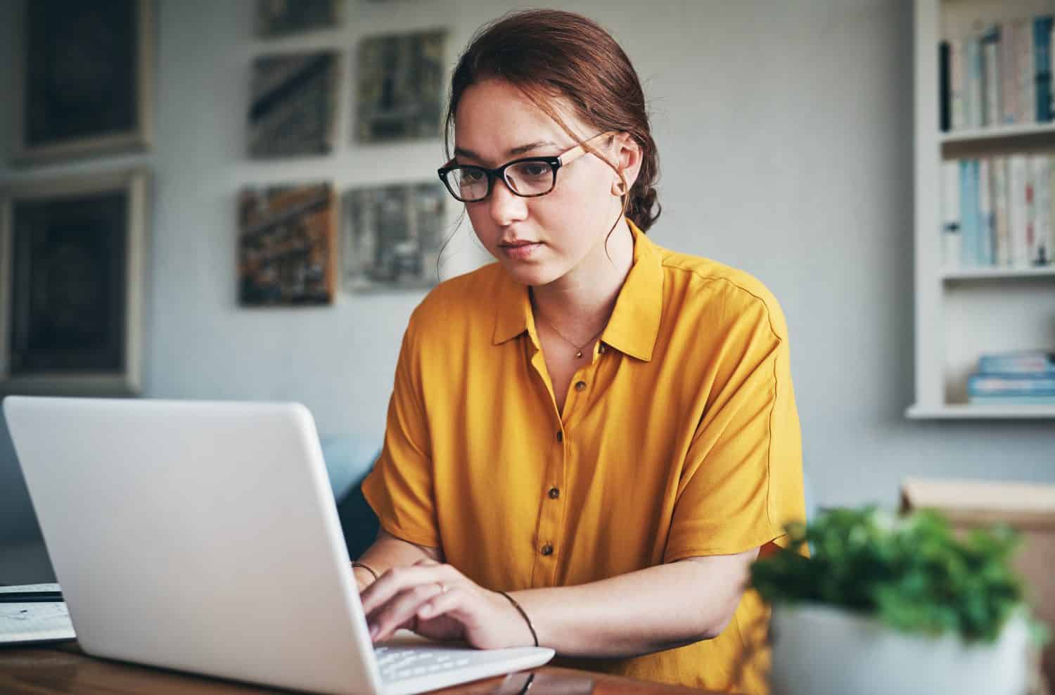 Woman, laptop and remote work for freelancer in home, online and research for writing article. Female person, check report and editing language on transcription, typing and upload journal on website