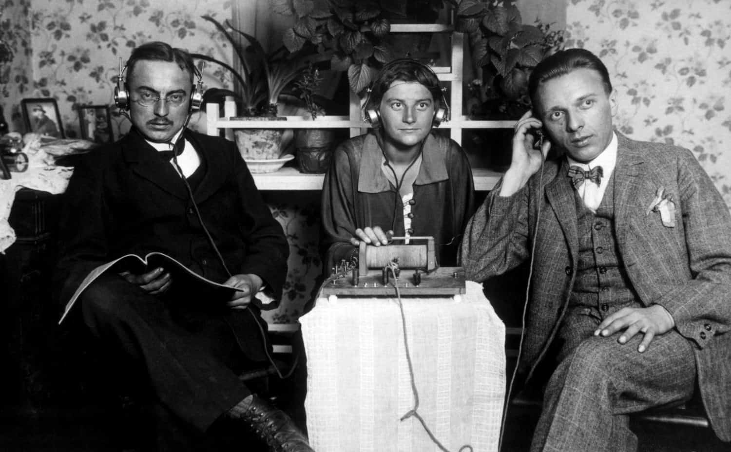 Three people listening to an early radio, c. 1925