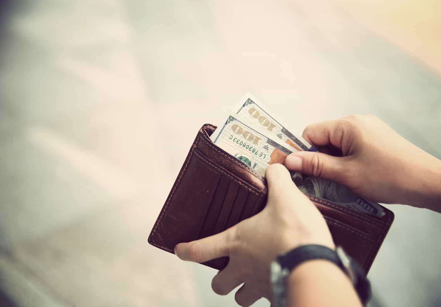 Hands taking out money from wallet on street