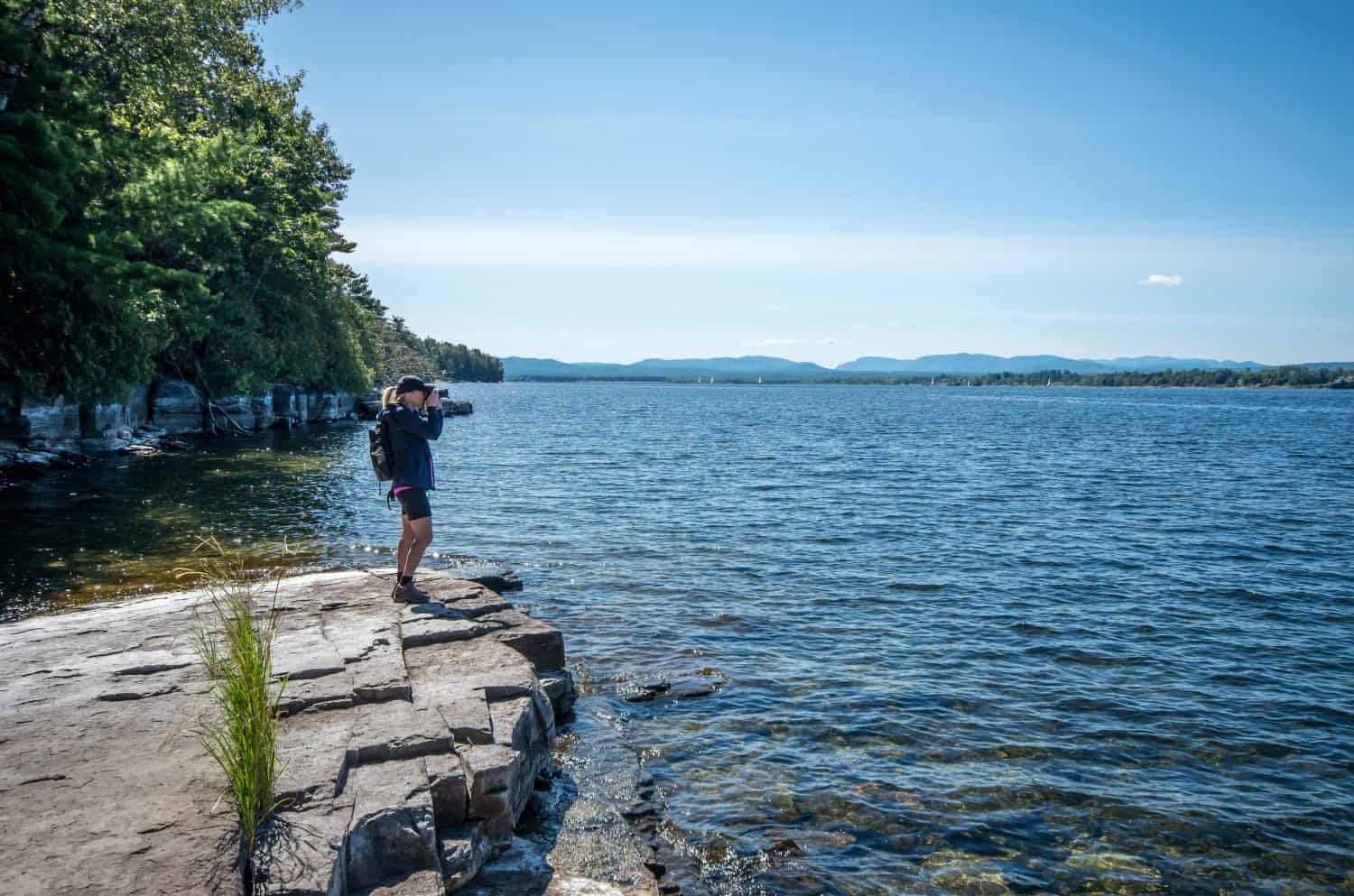 Woman taking a photo from the shore of Valcour Island