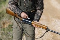 Unrecognizable hunter man loading shotgun with ammunition to hunt.