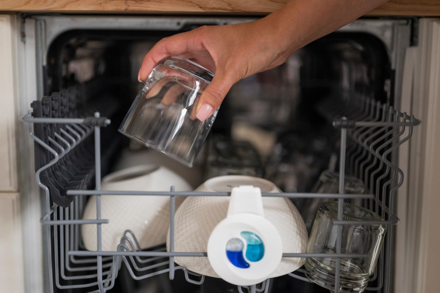 girl puts a glass in the dishwasher in the kitchen