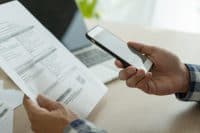 business man use phone to scan barcode or QR codes to pay credit card bill after receiving document invoice online. payment, receive, paying electricity, digital payments without money, technology