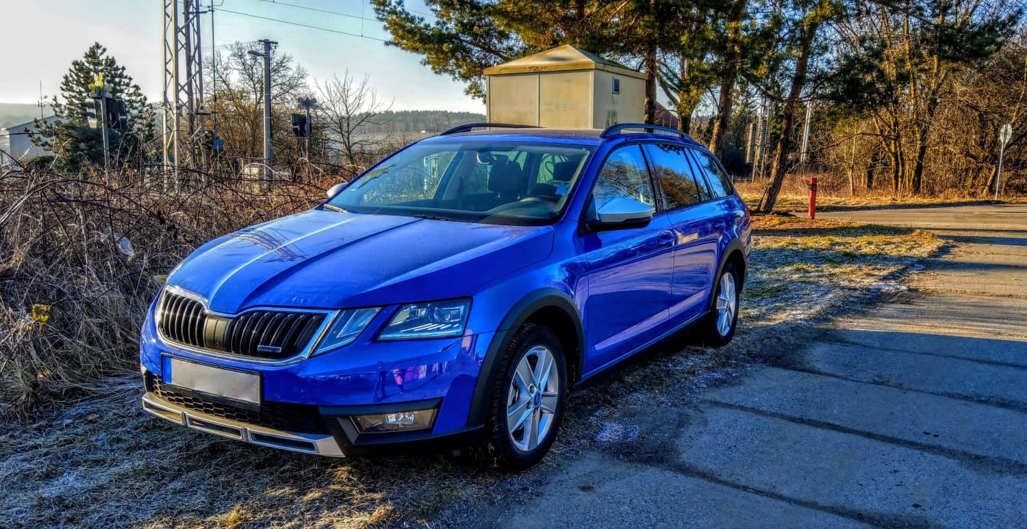 Blue new Skoda car with sunrise in winter sunny morning near railway track