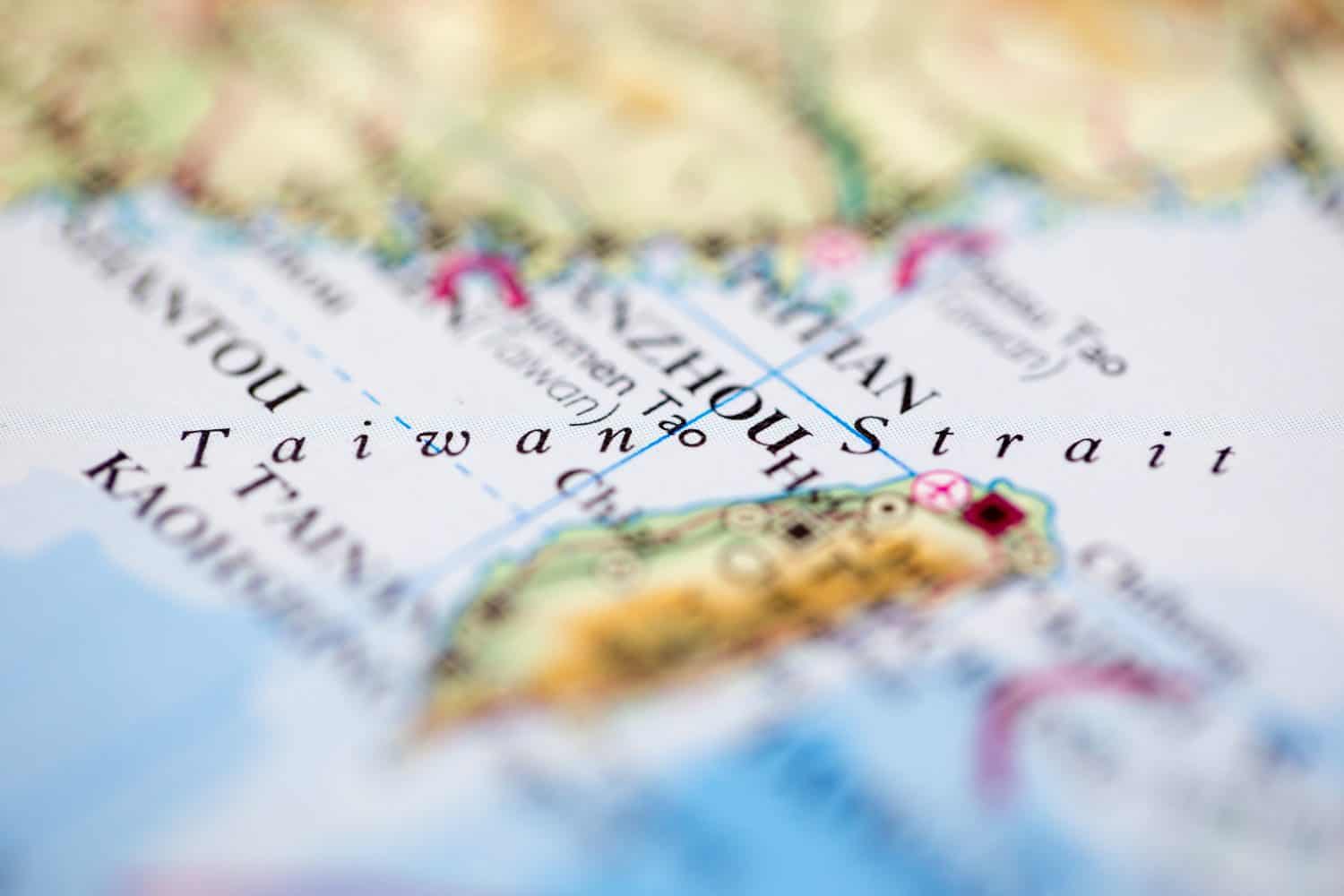 Shallow depth of field focus on geographical map location of Straits of Taiwan off coast of Taiwan on atlas