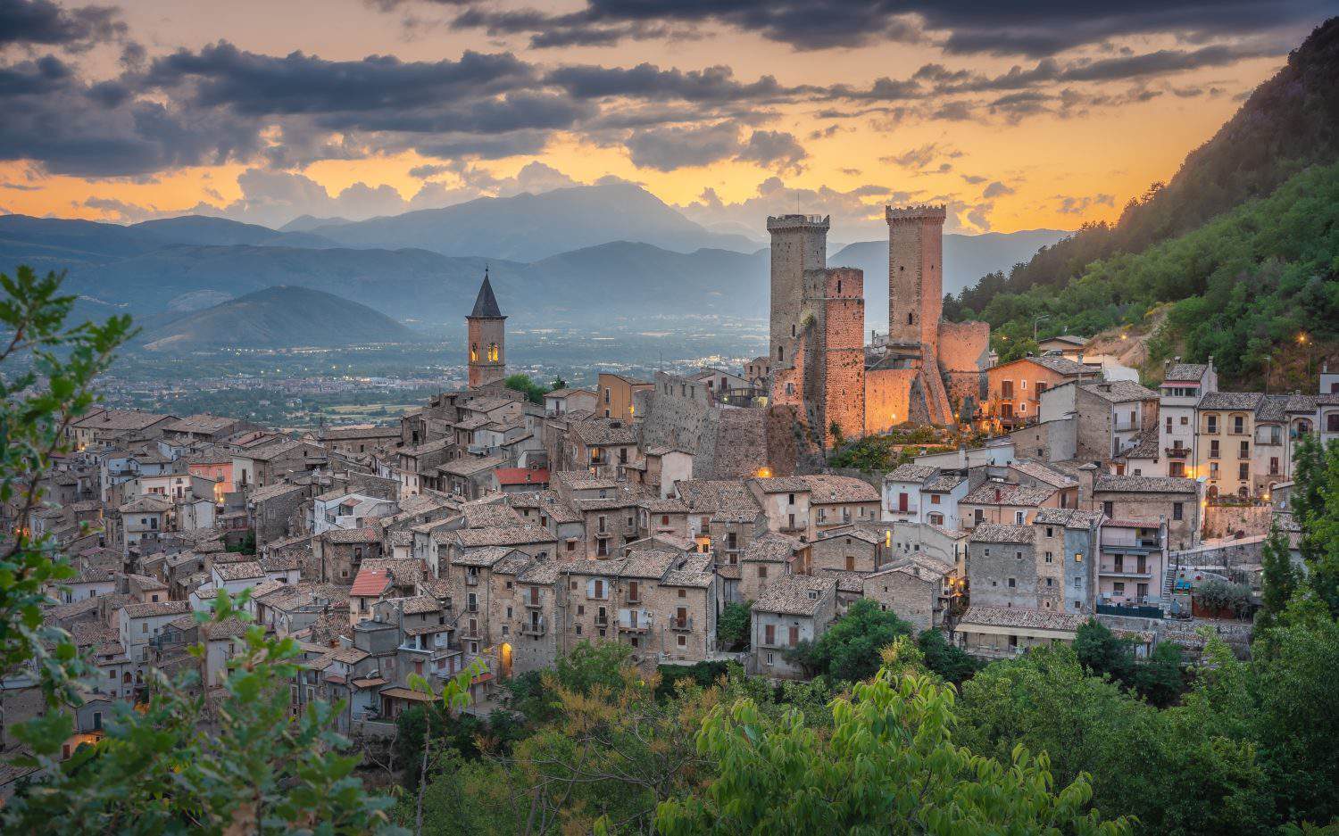 The picturesque village of Pacentro (Aburzzo, Italy) with its two big medieval towers with a splendid cloudy sky during the golden hour.