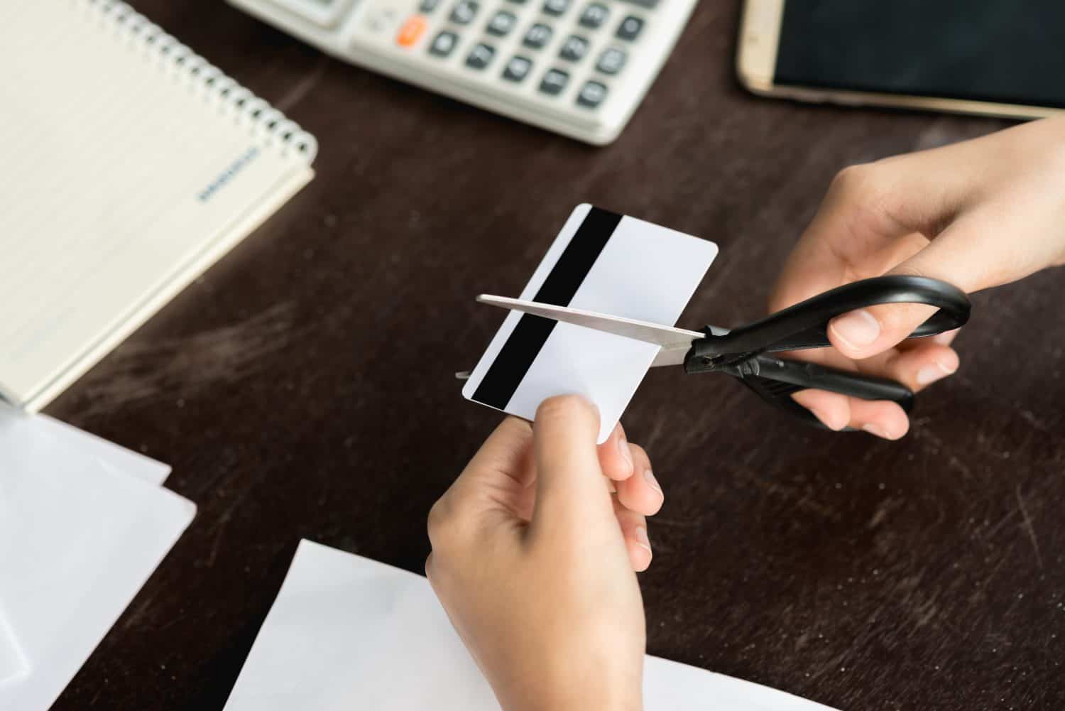 Financial or technology concept : Close up hands of people decide to cancel credit card by using scissors cut credit card for prevent expense over card limit.