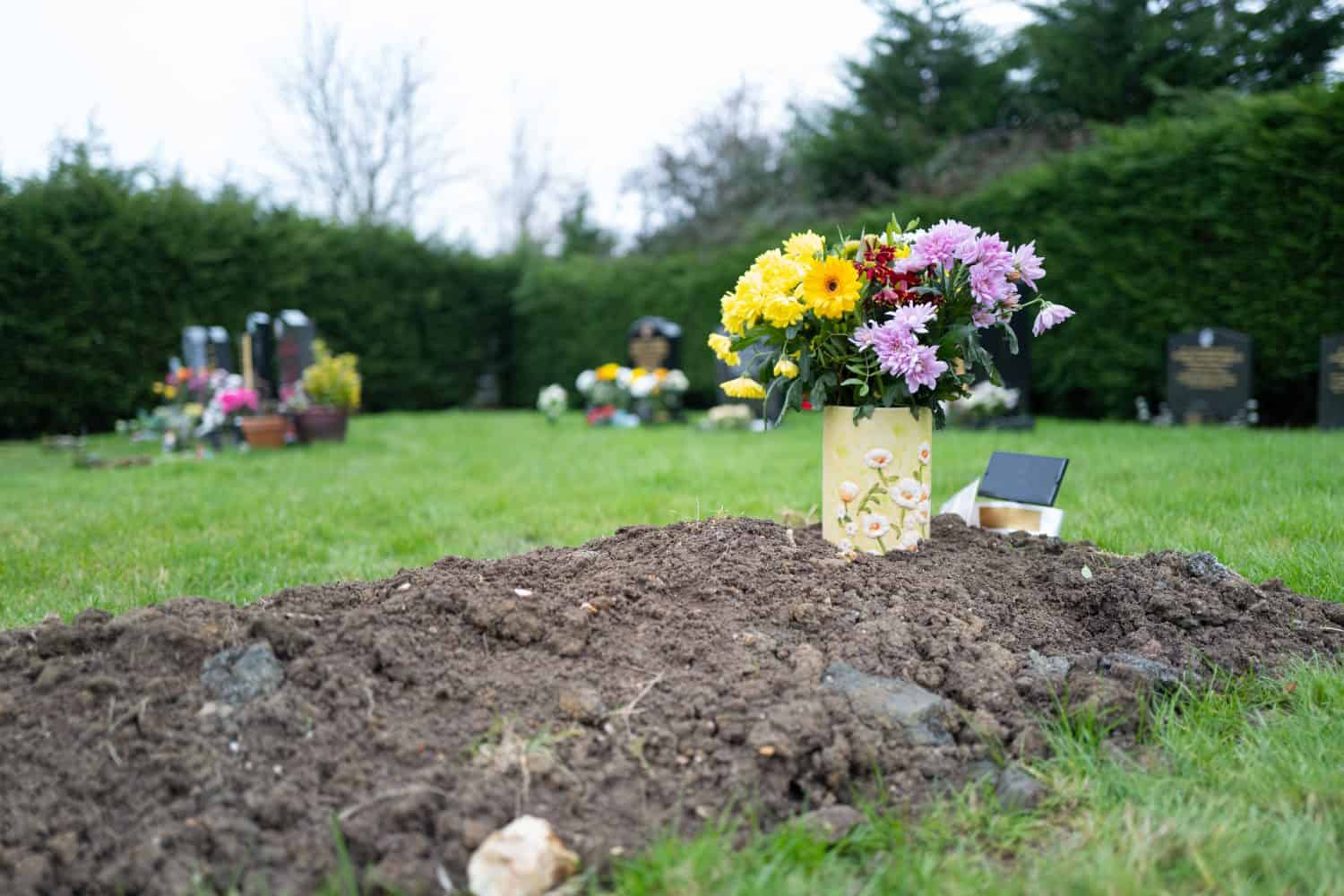 Shallow focus of a small bunch of pretty flowers seen on a freshly dug grave in a rural cemetery.