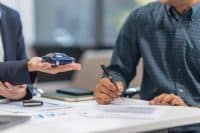 Asian businesswoman specializing in car loan services. Proficient in terms like extended warranty, lease, MSRP, and navigating financing options for customers' automotive needs.
