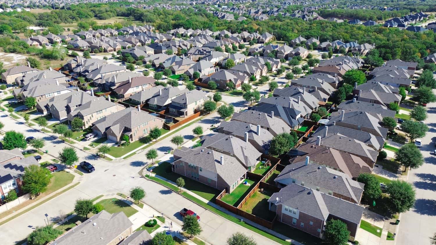 Large scale master planned community row of suburban residential houses in Bartonville and Argyle, Denton County, Texas, two story homes with shingle roofing, compact backyard, lush green trees. USA