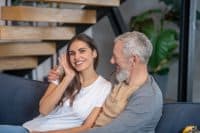 Generation gap. A smling woman hugging her handsome aged spouse