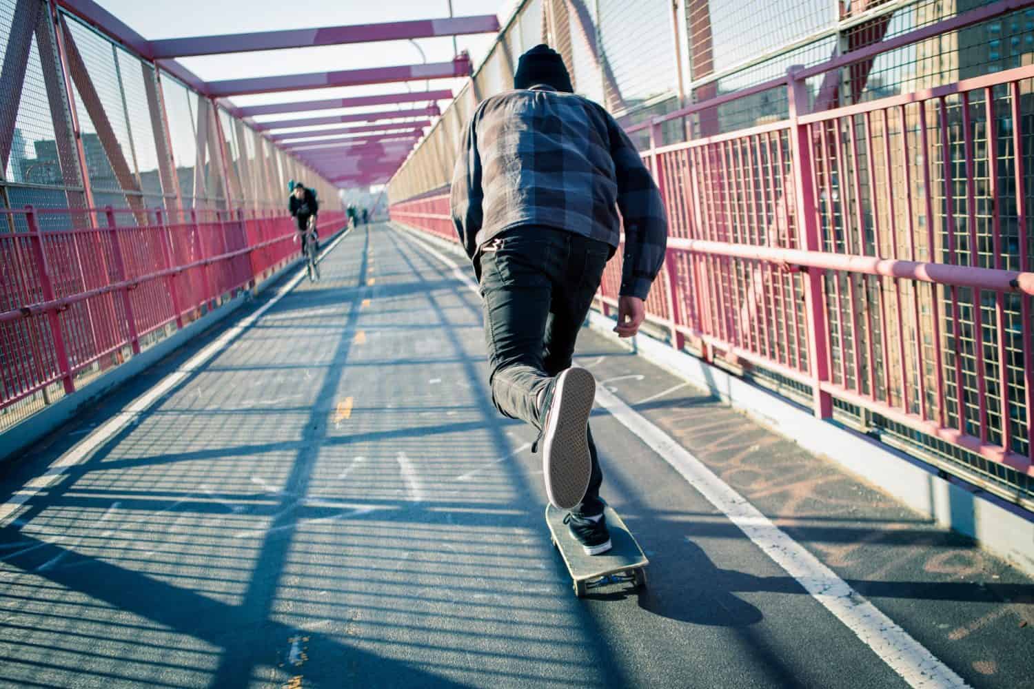 Young skateboarder speed through the pedestrian walkway on Williamsburg Bridge, NYC. Photographed in Feb 2016.