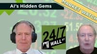 Two men, one wearing headphones, discuss financial markets in a video call format. The background is a blurred green screen with digital numbers, simulating stock market data. Overlays include a dark green banner 'Al's Hidden Gems', a yellow diagonal ribbon 'MARKET WATCH', and a green '24/7 WALL ST' logo, indicating a financial news segment.