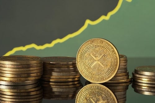 Golden XRP coins are displayed in front of green and blue financial graphs representing market trends and cryptocurrency fluctuations in a modern setting.