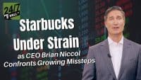A man in a checkered suit and white shirt speaks, framed on the right side of the screen. To his left, large white text reads 'Starbucks Under Strain as CEO Brian Niccol Confronts Growing Missteps.' In the top left corner is the green and black logo for '24/7 WALL ST.' The background is a blurred digital display showing financial numbers and charts in green, red, and white.