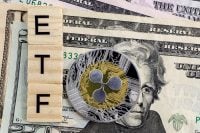 A close-up shot of three light-colored wooden blocks, stacked vertically, spelling 'ETF' in black letters. To their right, a shiny silver and gold Ripple (XRP) cryptocurrency coin partially covers US dollar banknotes, which form the background. The coin features a circuit board design around its perimeter and the distinctive three-lobed XRP logo in the center.
