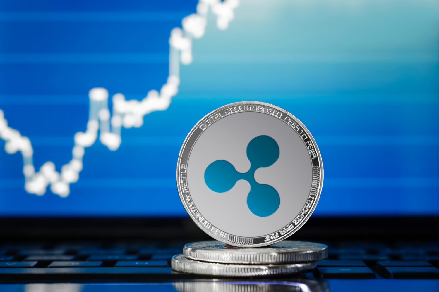 RIPPLE (XRP) cryptocurrency; silver ripple coin on the background of the chart