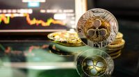 Ripple coins (XRP) Placed on a black floor with reflection and behind have graph is shown on the monitor. Concept Direction of the XRP coin.