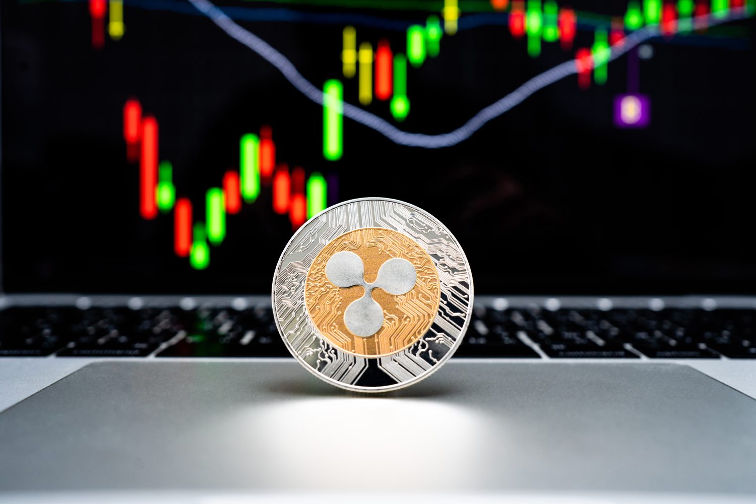 Cryptocurrency coin - Ripple coin is placed on a laptop with a graph background in the computer screen.