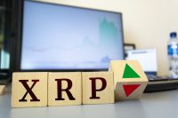 Wooden cubes with the inscription XRP and a cube symbolizing the rise and fall of financial markets.