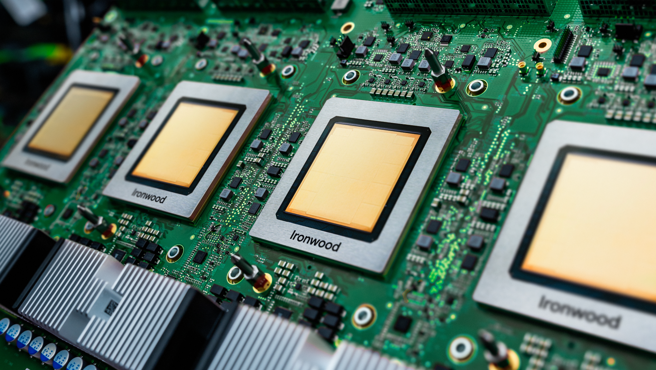 A close-up, angled view of a green circuit board populated with numerous small electronic components. Four large, square, metallic 'Ironwood' processor chips are prominently displayed, each featuring a golden-yellow rectangular center. Heat sinks are visible along the bottom edge of the board, indicating a high-performance system.