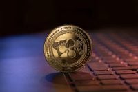 Ripple XRP cryptocurrency physical coin placed on laptop keyboard and lit with blue and purple lights