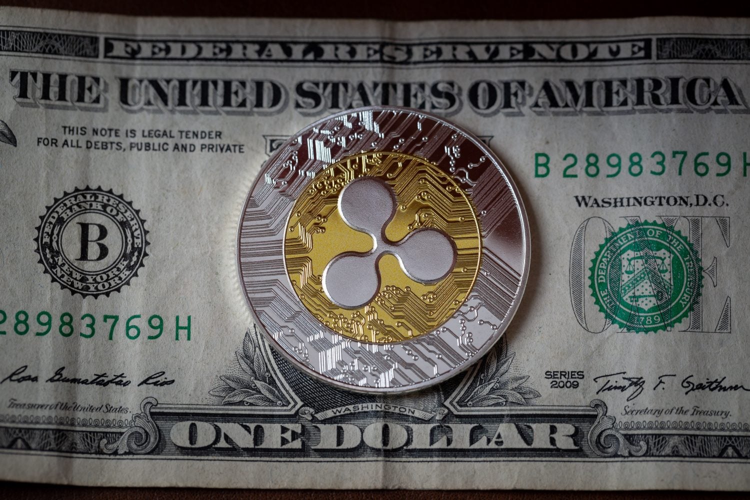 Ripple XRP cryptocurrency physical coin placed on one dollar bill. Macro shot. Selective focus.
