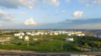 Aerial view of tank farm for bulk petroleum and gasoline storage next to rail line from Northeast of Houston. Crude oil storage terminal, pipeline operations, distributes petroleum products. Panorama.