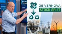 Jim Cramer, a bald man in a light blue shirt and patterned blue tie, points with both hands towards a blue financial news screen displaying stock information. To his right, a large graphic overlay features the green and white GE logo with text reading 'GE Vernova Stock Split'. An arrow points downwards from the logo to two teal gear icons. Below this, the graphic transitions into three photographic sections: a large industrial gas turbine, an electrical power substation with transmission lines, and several wind turbines silhouetted against a golden sunset, with a '24/7 WALL ST' logo in the bottom right corner.