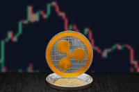 Ripple XRP on cryptocurrency coin with falling crashing graph in background. The cryptocurrency coin is golden and in focus. This is a price concept of Ripple down market.
