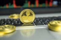 Golden Ripple coin with gold coins lying around on a black keyboard of silver laptop and diagram chart graph on a screen as a background. Mining of ripples online bussiness. Trading.