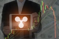 Blockchain concept : Rise and fall of Ripple price. Business man holding tablet showing Ripple symbol on screen with increasing and sharp falling price graph and dollar bills in background.