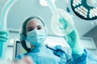 Doctor in medical mask and protective clothes standing with an anesthesia mask in her hand