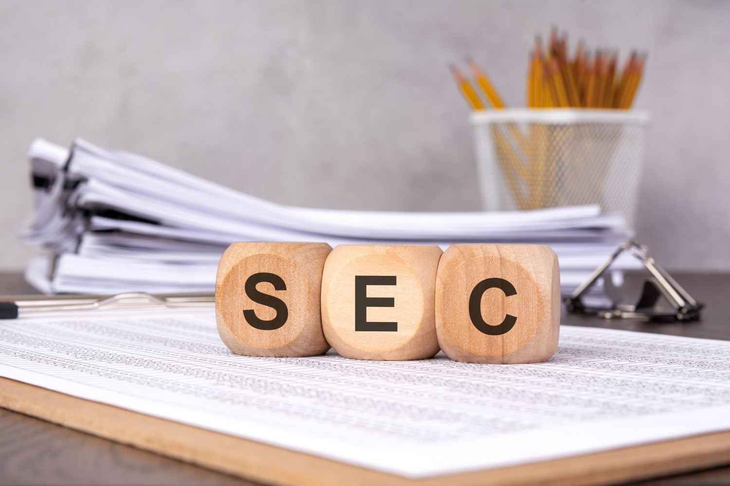wooden cubes with SEC on financial documents, with office supplies and papers in the background, symbolizing Securities and Exchange Commission