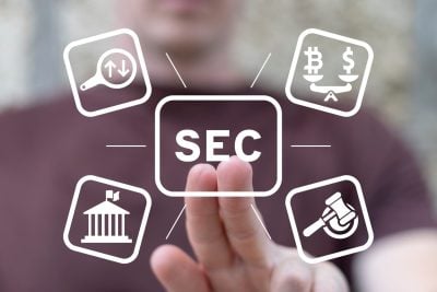 A person's hand reaches out to touch a glowing, central white square button labeled 'SEC'. Radiating from it are four other white outlined square icons: a magnifying glass with up and down arrows, a balance scale weighing Bitcoin and dollar symbols, a classical government building, and a judge's gavel. The background is a blurred image of a person and a warm-toned environment, suggesting a digital interface.