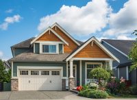 Real Estate Exterior Front House on a sunny day. Big custom made luxury house with nicely landscaped front yard and driveway to garage in suburbs. Modern designed home, New construction home exterior