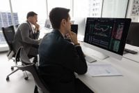 Financial trader man analyzing stock market, thinking on investment strategy, touching chin, looking at analytic data, growth chart on monitor, working on foreign exchange platform
