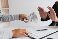 Business person refusing bribe given money by partner with anti bribery corruption concept.
