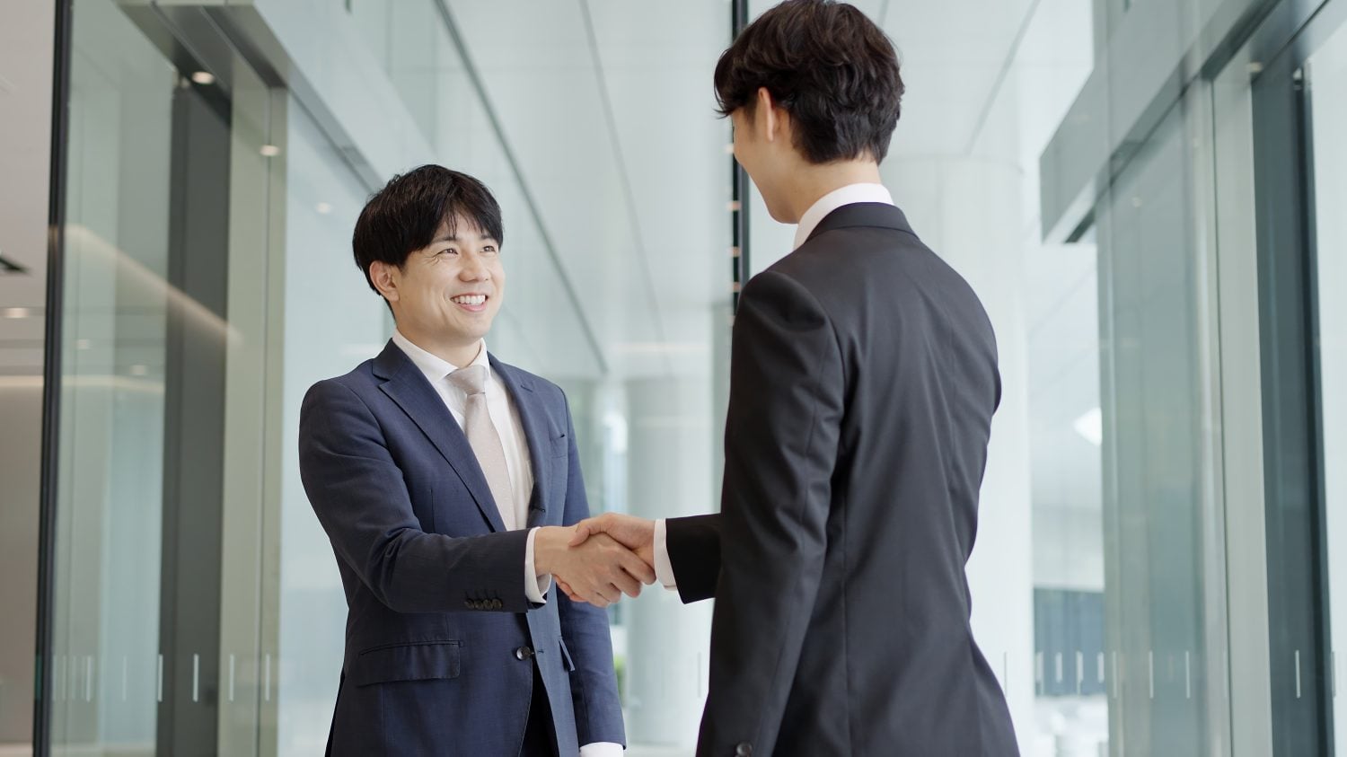 Asian businessmen shaking hands in a lobby