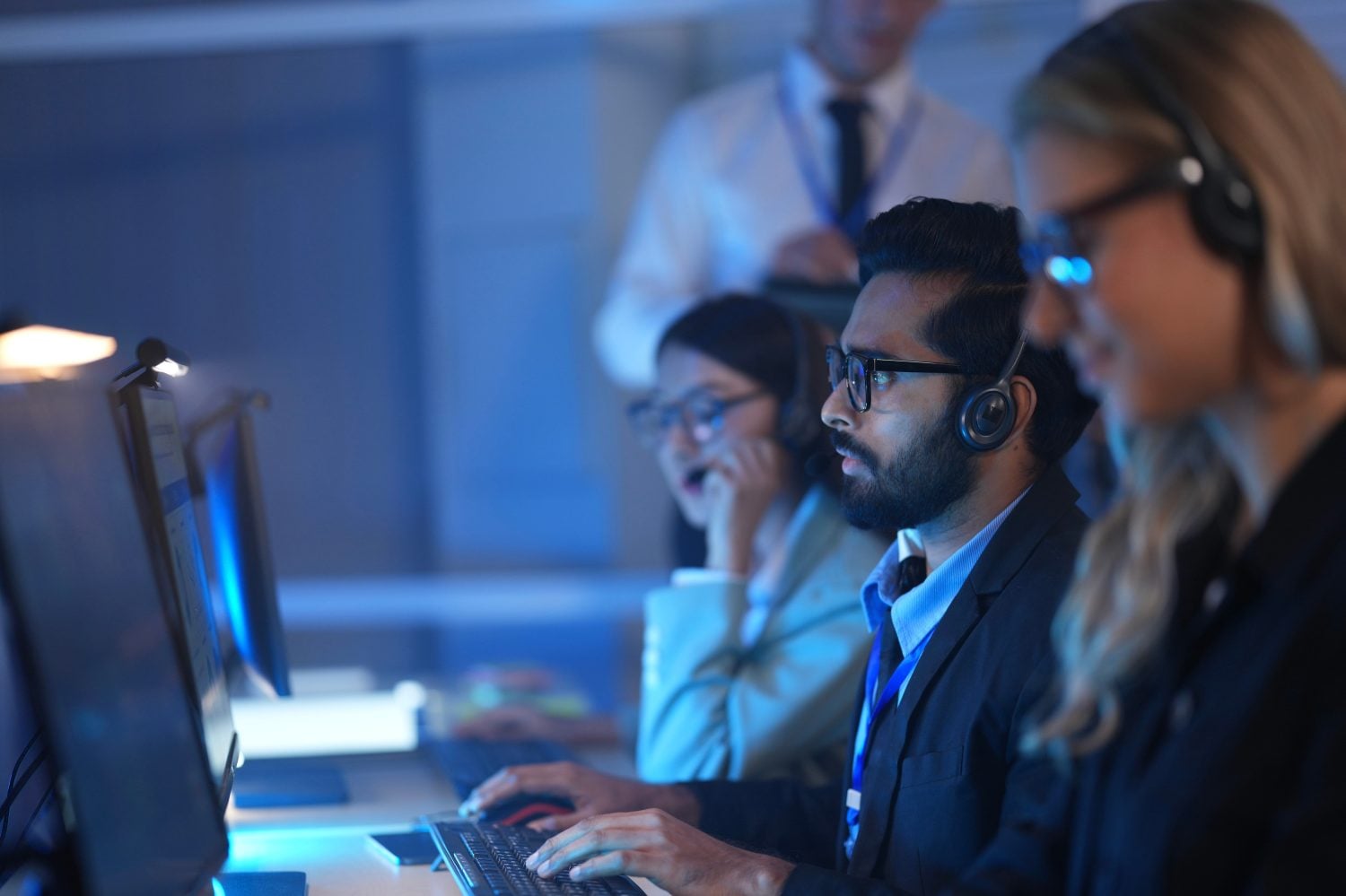 Command center lead focused intense monitoring critical systems late night headset connects team analyzing real time data screen crucial vigilance protects infrastructure operation underway now execut